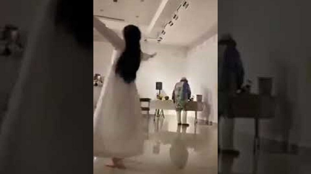 فتاة سعودية ترقص وتتمايل بفستان أبيض جريء في مركز الفن التشكيلي وهذا ما يفعله شاب بجوارها